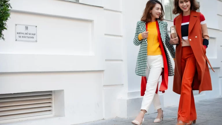 Two stylish women walking on city street in colorful outfits