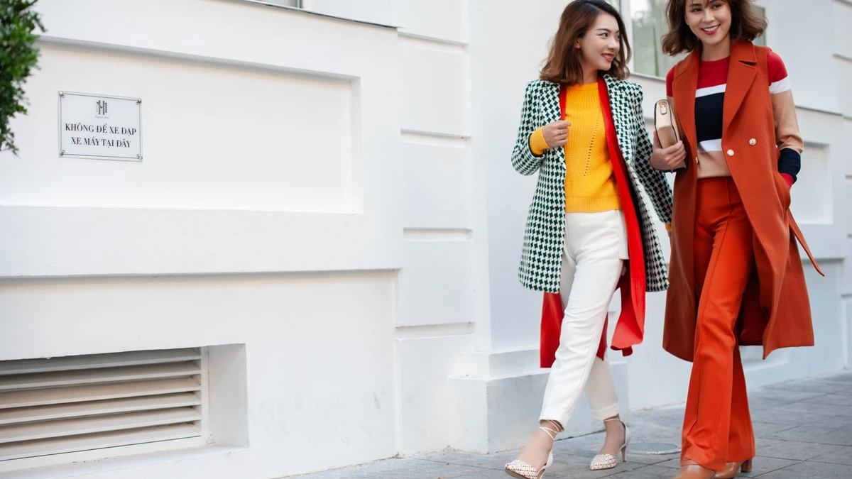 Two stylish women walking on city street in colorful outfits