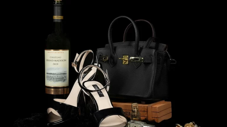 Luxury black handbag, shoes, and wine bottle paired with elegant jewelry create a sophisticated still life