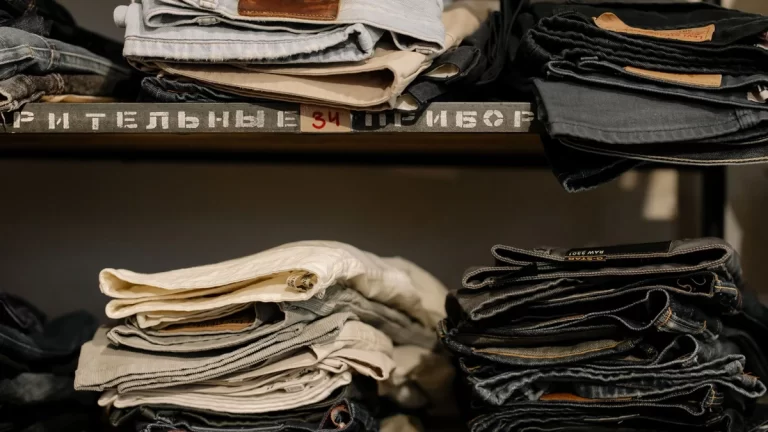 Folded jeans neatly stacked on shelves in a retail store, showcasing various styles and sizes