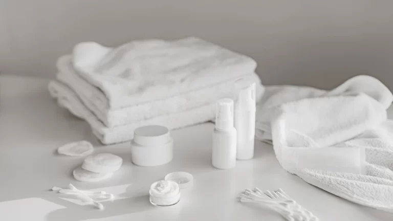 A neat arrangement of white skincare products and towels on a clean surface, perfect for spa and beauty themes