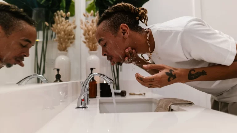 A man cleansing his face in the bathroom as part of a morning skincare routine
