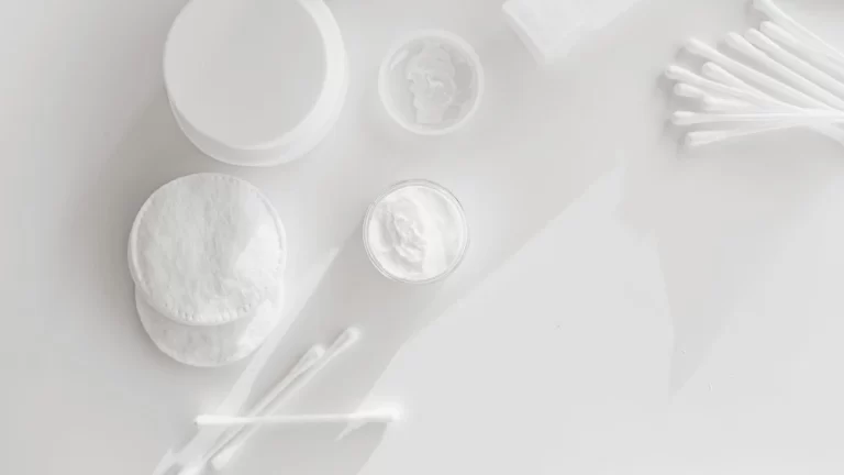 Flat lay of skincare essentials with cotton pads and cotton swabs on a white background
