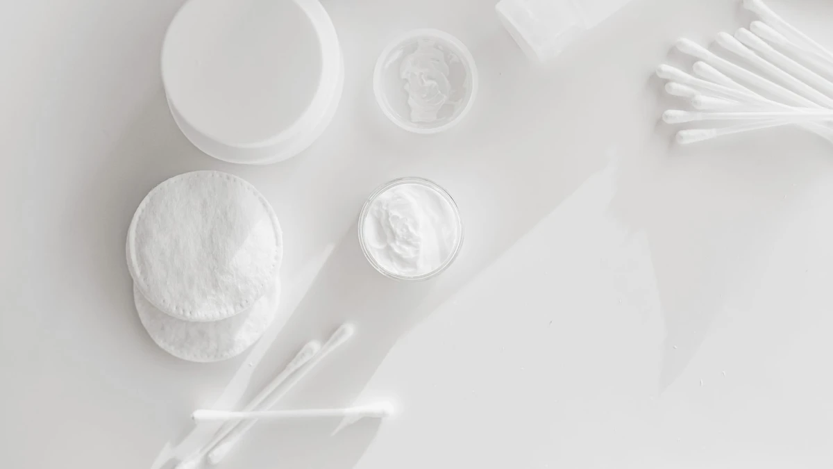 Flat lay of skincare essentials with cotton pads and cotton swabs on a white background