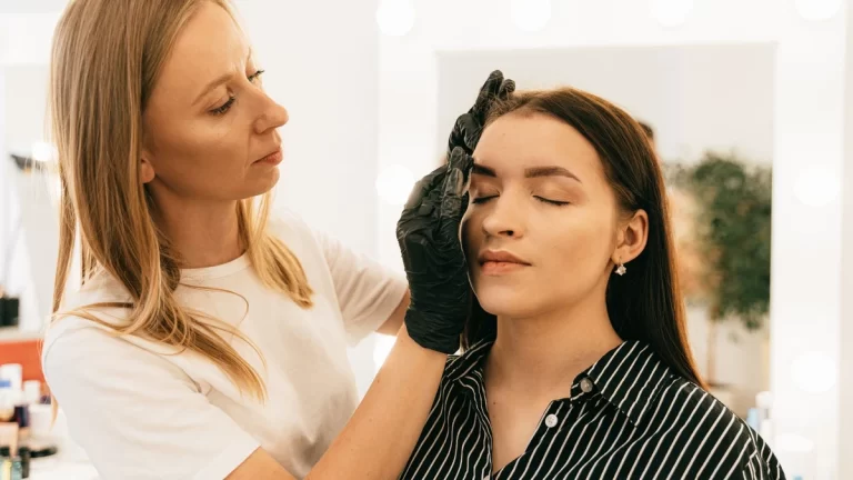 Makeup artist applying foundation in a well-lit studio setting, focusing on beauty and preparation