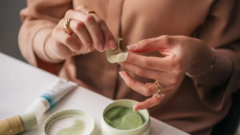 A woman applying green under eye patches for skincare routine