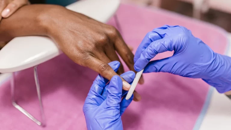 Close-up of hand receiving a manicure with latex gloves, showcasing precision and care