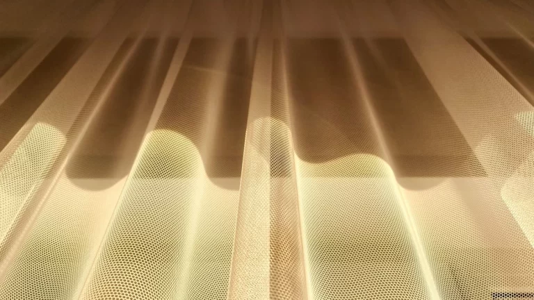 A low-angle shot of golden sheer curtains beautifully illuminated by sunlight