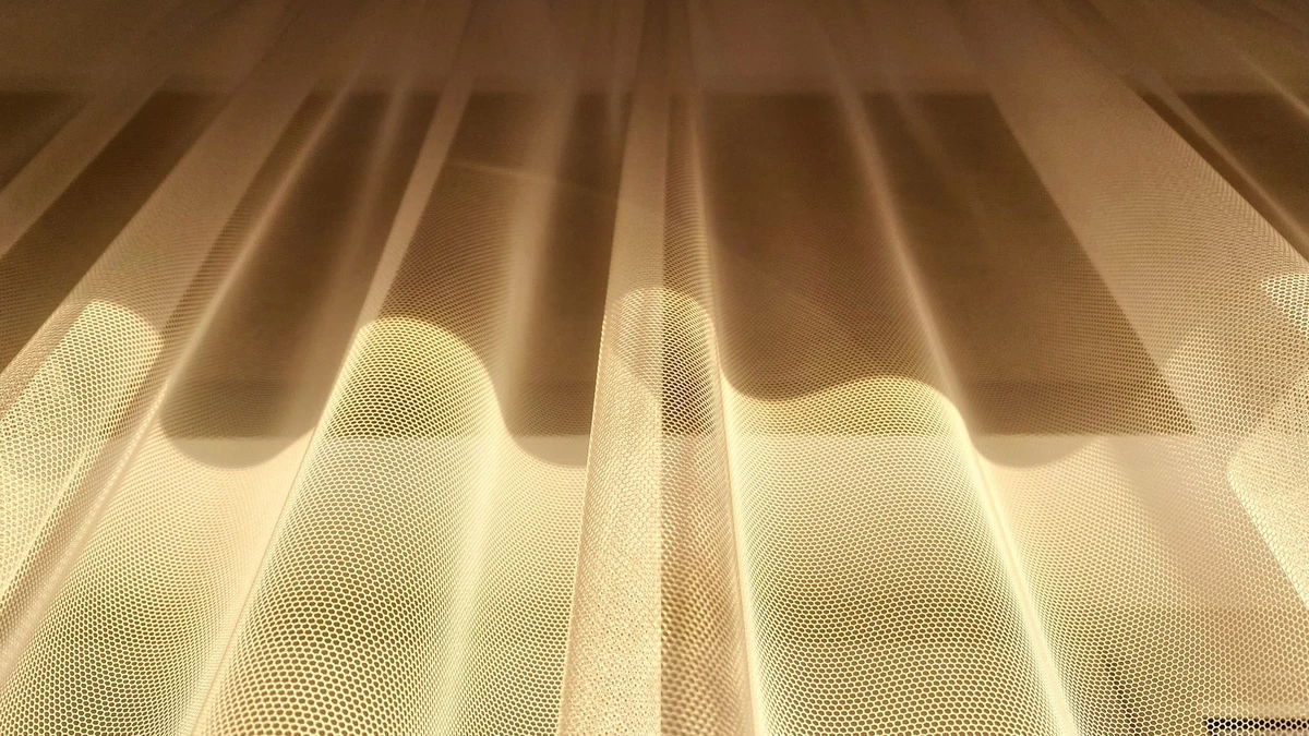 A low-angle shot of golden sheer curtains beautifully illuminated by sunlight